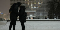 Ein Paar küsst sich im dunkeln vor einem Hotel.