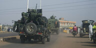 Millitärfahrzeuge mit Soldaten auf eine Straße.