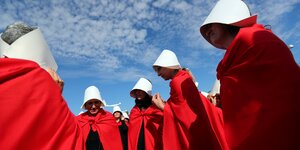 Das Foto zeigt eine Gruppe Frauen, die sich mit weißem Hauben und roten Mänteln nach der Serie "The Handmaid´s Tale" verkleidet haben, um zu protestieren .