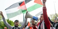 Zwei Demonstranten mit Megaphon vor palästinensischen Fahnen