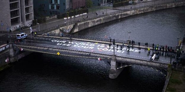 Aktivisten von Fridays For Future stehen auf einer Brücke und auf der Brücke steht: „Unsere Welt brennt, nutzt eure Stimme"