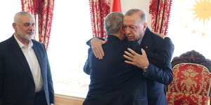 Hamas-Chef Haniyeh schaut lächelnd auf Erdogan, der Chaled Maschal umarmt