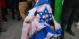 Eine verbrannte israelische Flagge liegt auf einem Mülleimer.