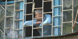 Ein Mann schaut nach einem nächtlichen russischen S-300-Raketenangriff auf Charkiw aus einem vergitterten Fenster